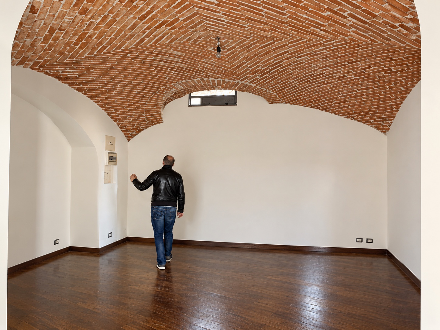 Sala con volta in mattoni, pareti bianche e parquet
